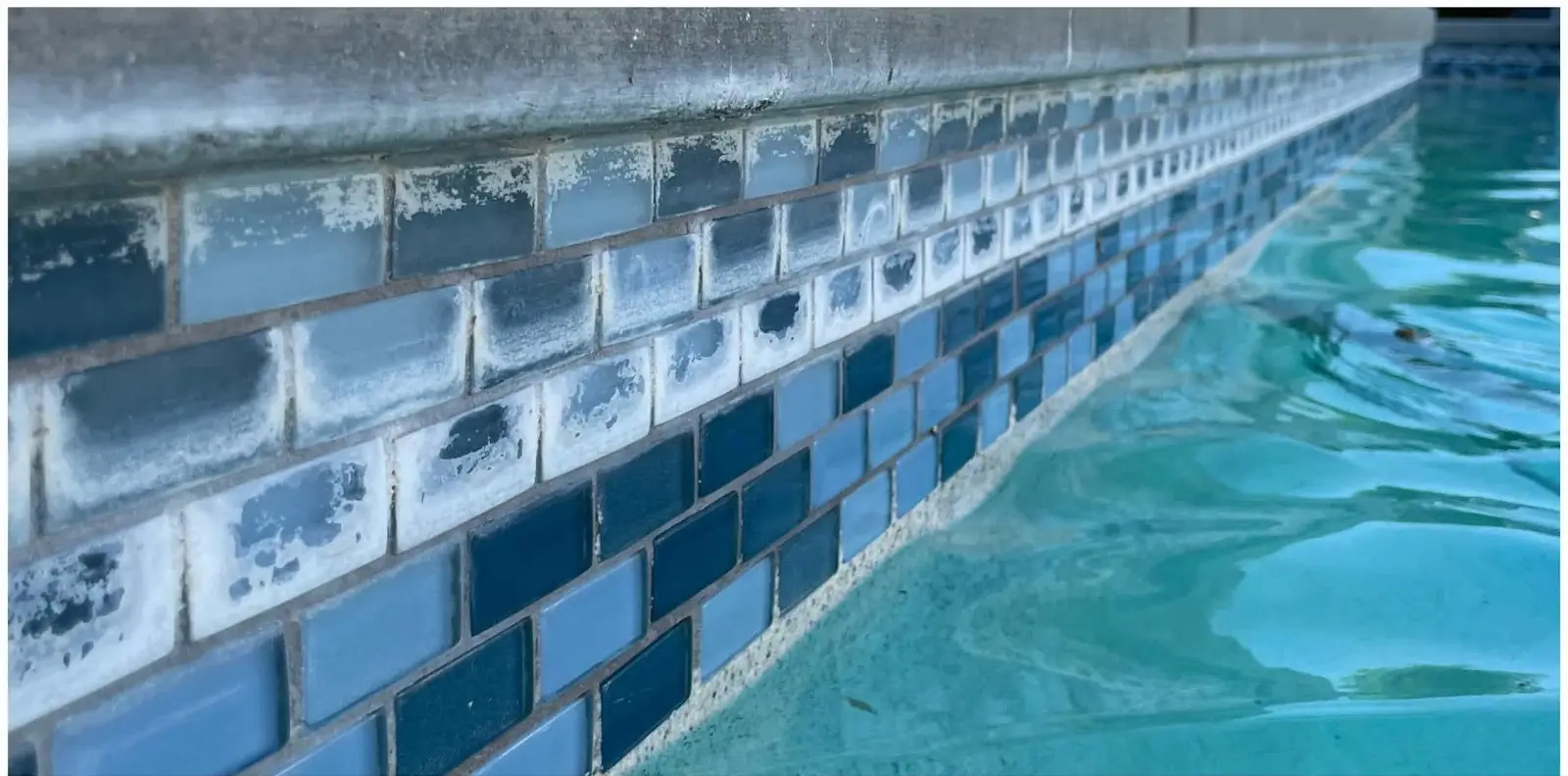 Blue glass waterline tile coated in white calcium